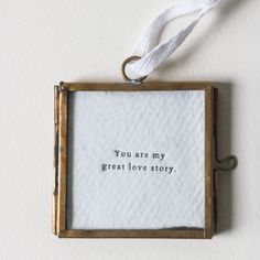 a small frame hanging on the wall with a string attached to it that says, you are my great love story