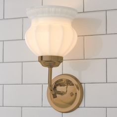 a bathroom light with a white glass shade on the wall next to a brick wall