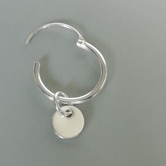 A PAIR of sterling silver hoops. Comes with a detachable tiny and delicate round disc charm. The charm is multipurpose and can be used with a neck or bracelet chain too. Dimension: Hoop- 12x1.2 mm Charm- 5 mm Drop length- 17 mm Price listed is for ONE PAIR These are made of 925 hypoallergenic sterling silver. Most of my pieces come with a 925 stamp. Can be packaged in a gift box. I can include a personal message from you if needed You are welcome to contact me at... bhavnakwintra1956@gmail.com F Minimalist Metal Small Hoop Huggie Earrings, Minimalist White Gold Huggie Earrings, Minimalist Metal Round Huggie Earrings, Minimalist Round Metal Huggie Earrings, Minimalist Sterling Silver Huggie Earrings With Charms, Silver Charm Earrings For Everyday, Silver Huggie Earrings With Charms In Small Hoop Shape, Silver Minimalist Single Hoop Earring, Minimalist Huggie Dangle Earrings With Charms