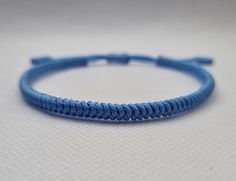 "Light Blue Lucky Knot Bracelet made from nylon cord. This knotted bracelet is designed for both genders males and females. *Size  S - Fully Closed - 5.9\"inches (15cm) / Full Opened - 9.8\"inches (25cm) M - Fully Closed - 6.6\"inches (17cm) / Full Opened - 10.6\"inches (27cm) L - Fully Closed - 7.4\"inches (19cm) / Full Opened - 11.4\"inches (29cm) Made from 1mm nylon cord. - - - - - - - - Blue colors benefits in a spiritual way: - Serenity and Tranquility: Light blue represents a sense of calmness, peace, and tranquility. It brings to mind clear skies and serene oceans, creating a harmonious atmosphere. - Spirituality and Divinity: Blue is connected to the spiritual realm, symbolizing higher states of consciousness and divine connection. It represents wisdom, truth, and spiritual enlight Blue Braided Friendship Bracelets, Handmade Blue Nylon Cord Jewelry, Blue Nylon Cord Friendship Bracelets As Gift, Blue Nylon Cord Friendship Bracelet As Gift, Handmade Blue Braided Bracelets In Nylon Cord, Handmade Blue Braided Nylon Cord Bracelets, Blue Nylon Cord Friendship Bracelets With Sliding Knot, Handmade Blue Nylon Cord Braided Bracelets, Blue Sliding Knot Friendship Bracelets In Nylon Cord