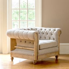 a white chair sitting in front of a window on top of a hard wood floor