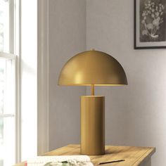 a table with a lamp on top of it next to a book and some pictures