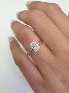 a woman's hand with a diamond ring on top of her finger and an engagement band