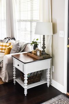 a living room with a couch, table and lamp on the floor in front of a window