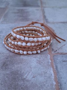 This Freshwater Pearl and Leather bracelet is the perfect combination of elegance and contemporary style. The bracelet wraps around the wrist 5 times and features beautiful cultured pearls and genuine leather. It's the perfect accessory to add a touch of sophistication to any outfit. This pearl wrap bracelet is a versatile accessory that can be dressed up or down. Choose from natural tan leather or dark brown leather. Adjustable sizing with button closure allows for a comfortable and secure fit Elegant Multi-strand Adjustable Wrap Bracelet, Adjustable Cream Pearl Bracelet, Elegant Handmade Adjustable Leather Bracelet, Elegant Adjustable Hand Wrapped Pearl Bracelet, Adjustable Pearl Bracelets, Adjustable Cream Pearl Bracelets, Elegant Beaded Leather Bracelet Gift, Elegant Adjustable Hand Wrapped Bracelet, Elegant Hand Wrapped Leather Bracelet Gift