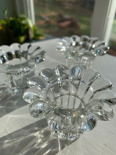 three clear glass vases sitting on top of a white table cloth covered tablecloth