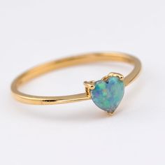 a yellow gold ring with an opal stone in the shape of a heart, on a white background