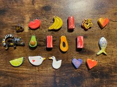 several different types of fruit and vegetables are arranged on a wooden surface, including bananas, oranges, avocado, banana slices, and other fruits