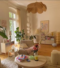 a living room filled with furniture and lots of plants on top of a table in front of a window