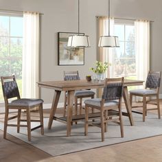 a dining room table with four chairs and a rug in front of the window,