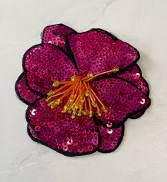 a pink flower with sequins on it sitting on top of a white surface