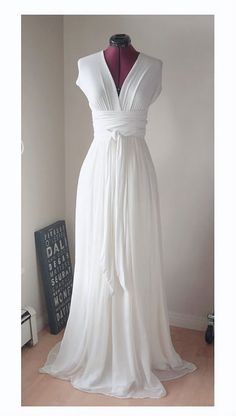 a white dress on a mannequin stand in front of a wall