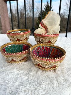 three decorative bowls sitting on top of a white blanket