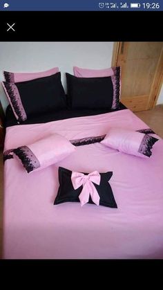 a bed with pink sheets and black pillows