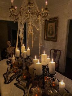 a table topped with lots of lit candles next to a chandelier filled with skulls