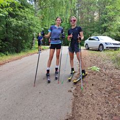 two people on skis are standing in the middle of a road with their poles