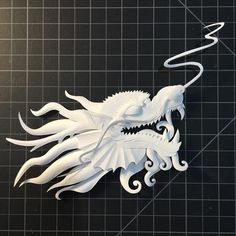 a paper sculpture of a white dragon on a black surface