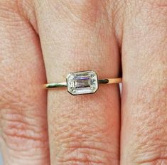 a woman's hand with a ring on it that has an emerald stone in the middle