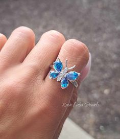 Blue Topaz CZ butterfly silver ring, clear - butterfly ring, silver ring, promise ring - 925 sterling silver  Height: 16.0mm Width: 17.0mm Shank Width: 1.7mm Stone Material: Blue Topaz CZ and White Cubic Zirconia Center Stone Size: 7.0mm x 5.0mm & 6.0mm x 4.0mm Stone Shape: Pear and Round Center Stone Carat Weight: 0.71 ct. & 0.39 ct. Number of CZ Stones: 8 Stone Setting: Prong Metal: 925 Sterling Silver Plating: Rhodium Finish: High Polish simply stunning. High Polished, solid 925 sterling silver. Rhodium plated to prevent tarnishing. TARNISH FREE Rhodium plated to avoid tarnishing Nothing but the best from my custom jewelry store. Email me if you have any questions. Butterfly Charm Ring For Anniversary, Elegant Sterling Silver Rings With Butterfly Charm, Butterfly-shaped Sterling Silver Jewelry For Wedding, White Gold Butterfly Ring For Anniversary, Sterling Silver Butterfly Birthstone Jewelry, Butterfly-shaped Cubic Zirconia Wedding Rings, Butterfly Cubic Zirconia Wedding Rings, Silver Butterfly Jewelry With Birthstone, Silver Butterfly Ring For Wedding