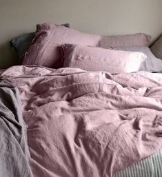 an unmade bed with pink sheets and pillows