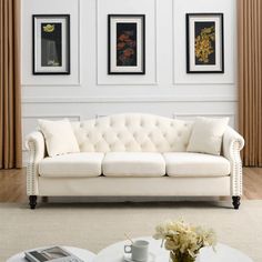 a white couch sitting in front of two pictures on the wall above a coffee table