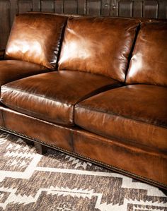 a brown leather couch sitting on top of a rug