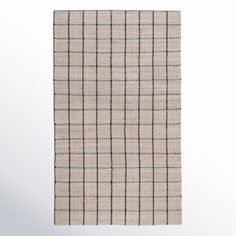 a beige and black checkered rug hanging on a wall in front of a white background