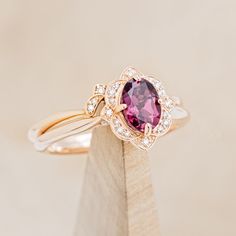 a close up of a ring with a pink stone in the center and diamonds around it