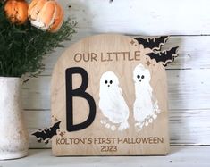 a wooden sign that says our little b and two ghostes are in front of some pumpkins