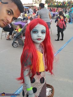 a person with red hair and makeup standing next to a child in a halloween costume