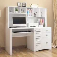 a white computer desk with drawers and a monitor on it's stand next to a window