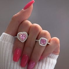 a woman's hand with two rings on her fingers and pink nail polishes