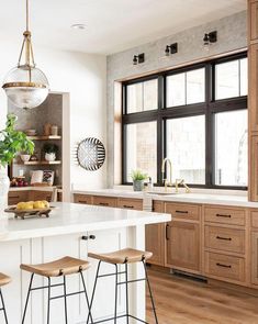 a large kitchen with wooden cabinets and white counter tops, along with two stools in front of the island