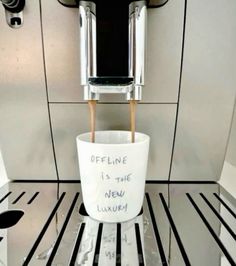 a coffee cup sitting on top of a machine in a room with black and white stripes