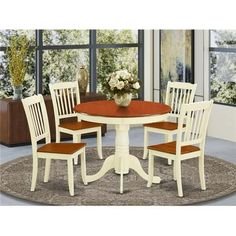 a dining room table with four chairs and a rug in front of the window,