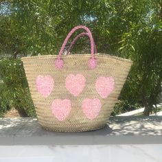 Our large hand woven straw tote with pink sequin hearts is such a sweet addition to the collection! It's made by hand with wicker palm straw that is sourced locally in Morocco. One side has hand sewn pink sequins in the shape of hearts and the other side is plain straw. Handcrafted in Morocco Straw with leather handles Individually hand sewn pink sequins 22"W x 13" H x 7.5"D (interior capacity - large) 7" strap drop Draw string liner that closes at the top of bag to secure your belongings Sustai Pink Handwoven Bucket Straw Bag, Handmade Pink Bucket Straw Bag, Pink Handwoven Basket Beach Bag, Handwoven Pink Basket Beach Bag, Handmade Pink Straw Tote Bag, Pink Straw Bag With Braided Handles, Pink Handwoven Straw Bag, Pink Handwoven Straw Bag For Summer, Princess Vibes