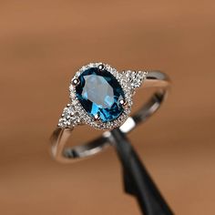 It is a London blue topaz ring. The main stone is 6mm*8mm oval cut, weight about 1.47carats. The basic metal is sterling silver and plated with rhodium.  To change the metal to a solid gold (white/rose) or platinum is also available, please ask for a quotation if you want.  You can also go to my shop Home for more elegant rings: https://www.etsy.com/shop/godjewelry?ref=hdr_shop_menu  More rings: https://www.etsy.com/shop/godjewelry?ref=l2... Oval Birthstone Promise Ring In 14k White Gold, Elegant Oval Birthstone Ring In 14k White Gold, Oval Birthstone Ring In 14k White Gold For Promise, Formal Oval Topaz Ring With Halo Setting, Classic Oval Birthstone Ring With Halo Design, Oval Cubic Zirconia Topaz Ring Birthstone, Oval Cubic Zirconia Topaz Birthstone Ring, Elegant Silver Birthstone Ring With Halo, Fine Jewelry Blue Topaz Diamond Ring