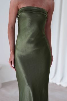 a woman in a green dress is posing for the camera