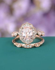 an engagement ring with a pink morganite surrounded by white diamonds on a green surface