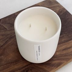 a white candle sitting on top of a wooden cutting board