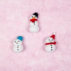 three crocheted snowmen on a pink background