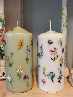 two candles with flowers painted on them sitting on a table next to other decorative items