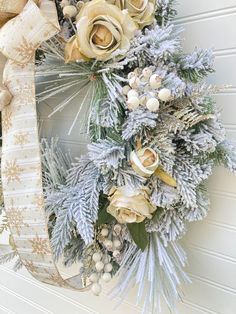 a christmas wreath hanging on the side of a door with white and gold decorations around it