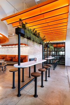 Custom white solid surface dining table and bar stools with modern medal legs. Cafe Mezzanine Interior Design, Playful Restaurant Design, Community Table Restaurant, Quick Service Restaurant Design, Restaurant Counter, Community Table, Cafe Seating, Communal Table