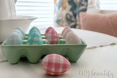 an egg carton filled with colored eggs sitting on top of a table next to a bowl