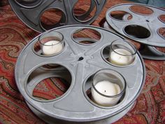 two old movie reels with candles in them sitting on the floor next to each other