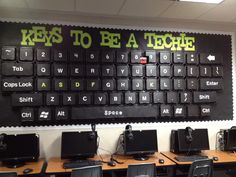 there are many computers on the desks in this room with words written on the wall