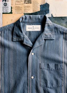 a blue shirt with white stripes is hanging on a wall covered in newspaper and papers