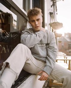 a young man sitting on top of a window sill