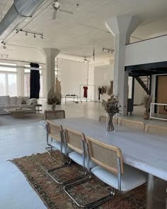 an empty room with tables and chairs in the foreground, several couches on the other side